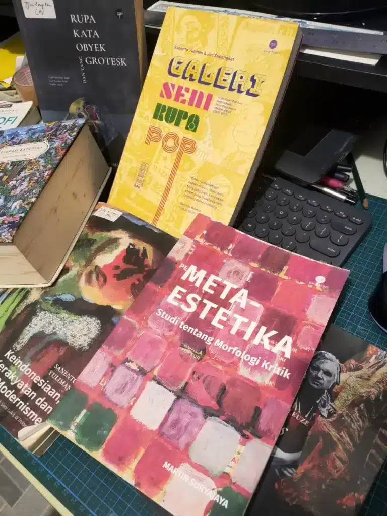 A collection of Indonesian art history and criticism books from Penerbit Gang Kabel on a work desk, featuring titles by Sanento Yuliman and Martin Suryajaya.