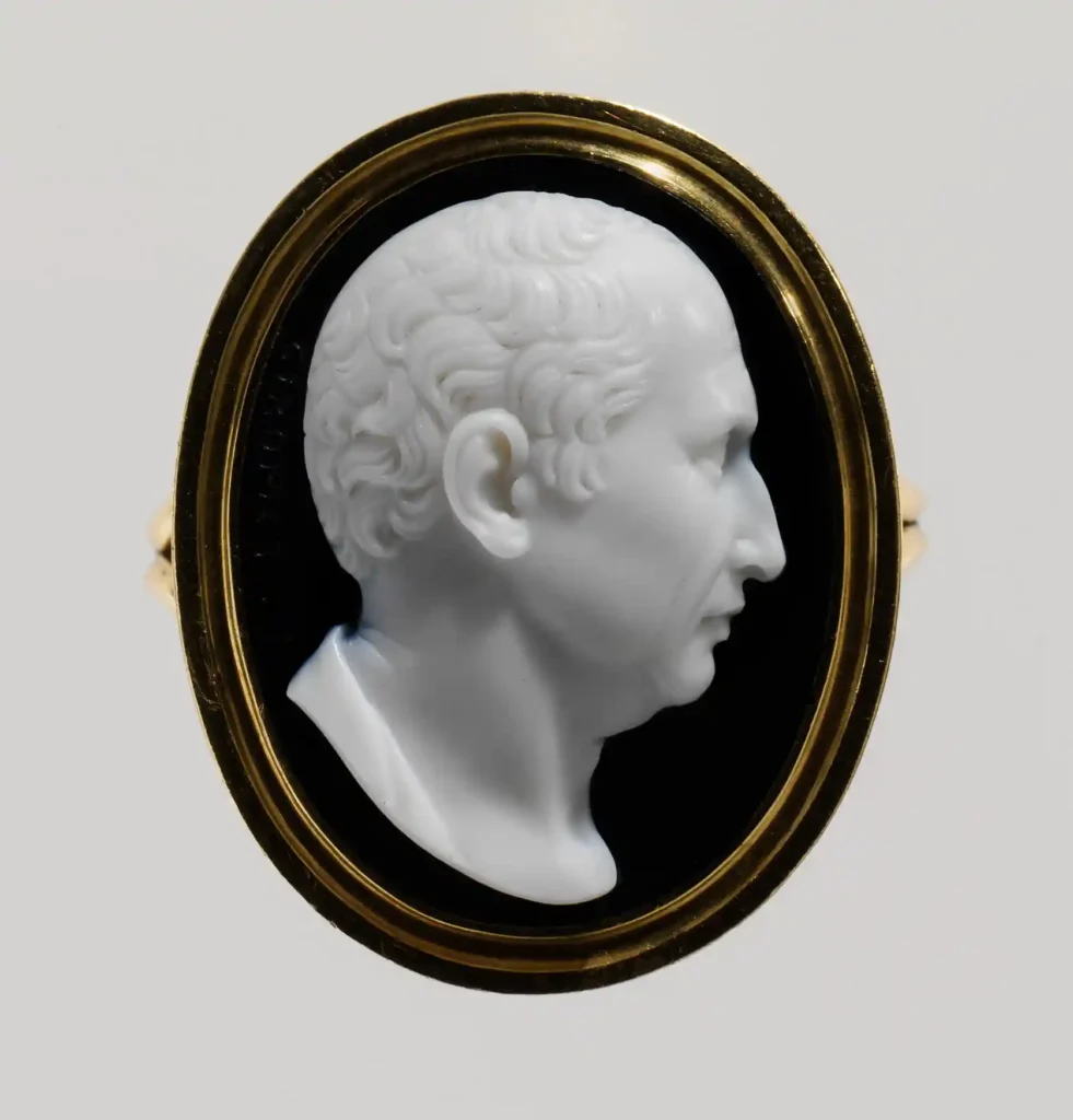 An oval onyx cameo portrait ring depicting the white profile bust of Roman philosopher Cicero against a dark background in a gold setting.